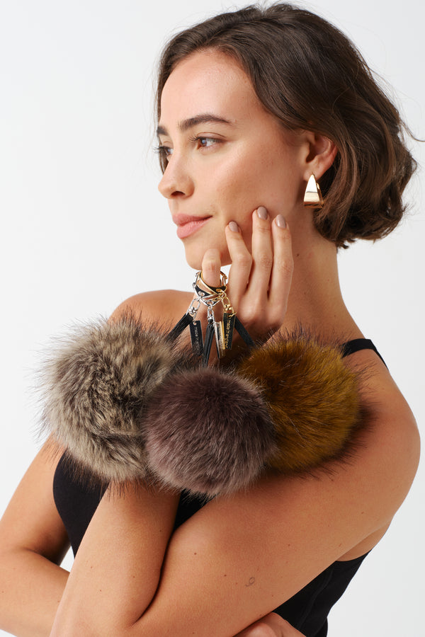 Model holding faux fur pom pom key ring bag charms by Helen Moore